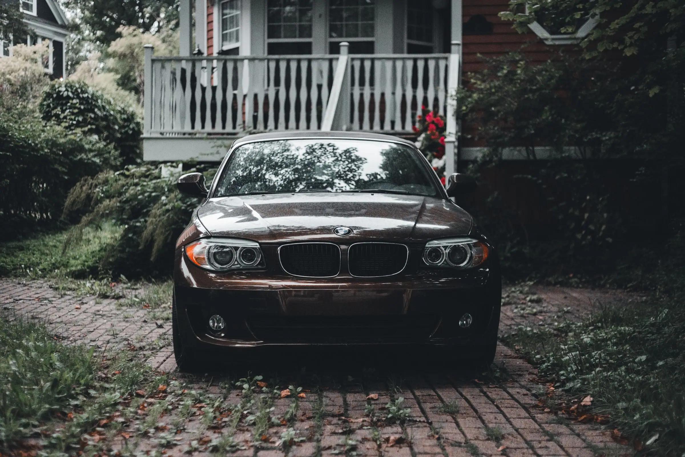 Car parked on a brick paver driveway in front of a house