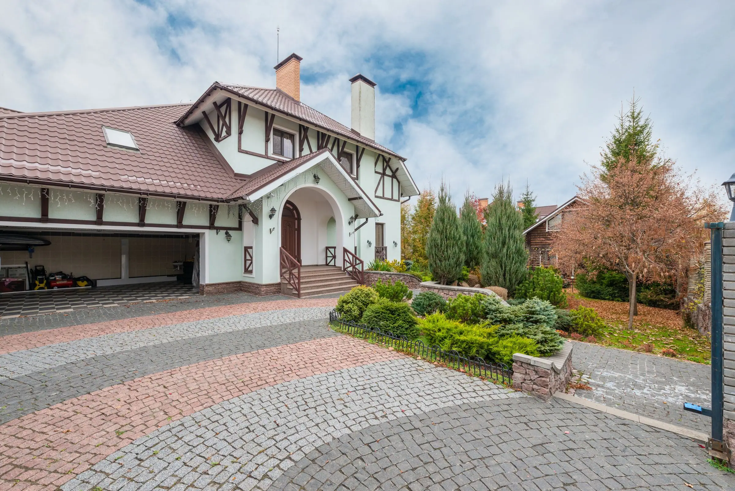 House with a wide paver driveway curving to the garage