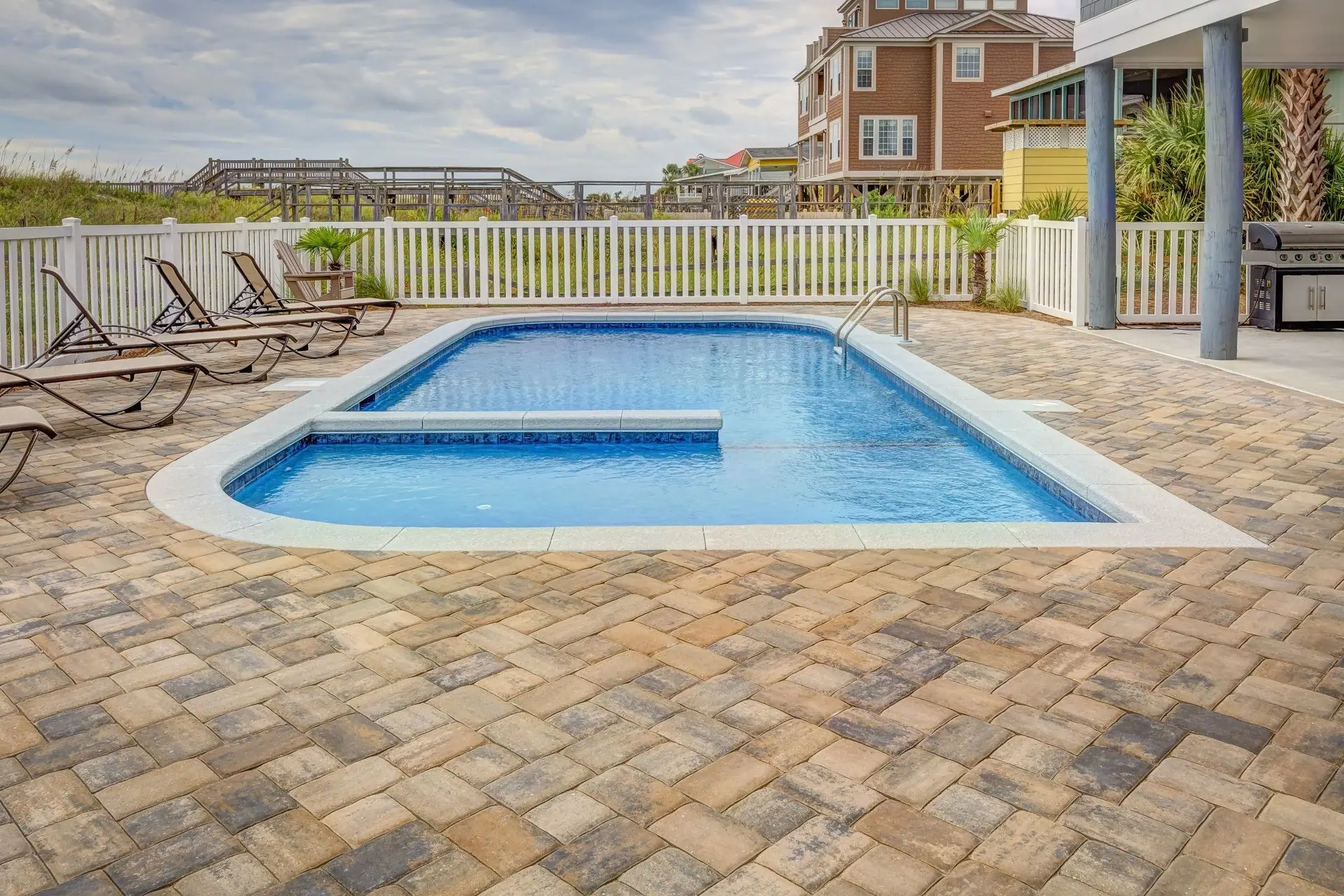 Pool surrounded by a wide paver deck with lounge chairs