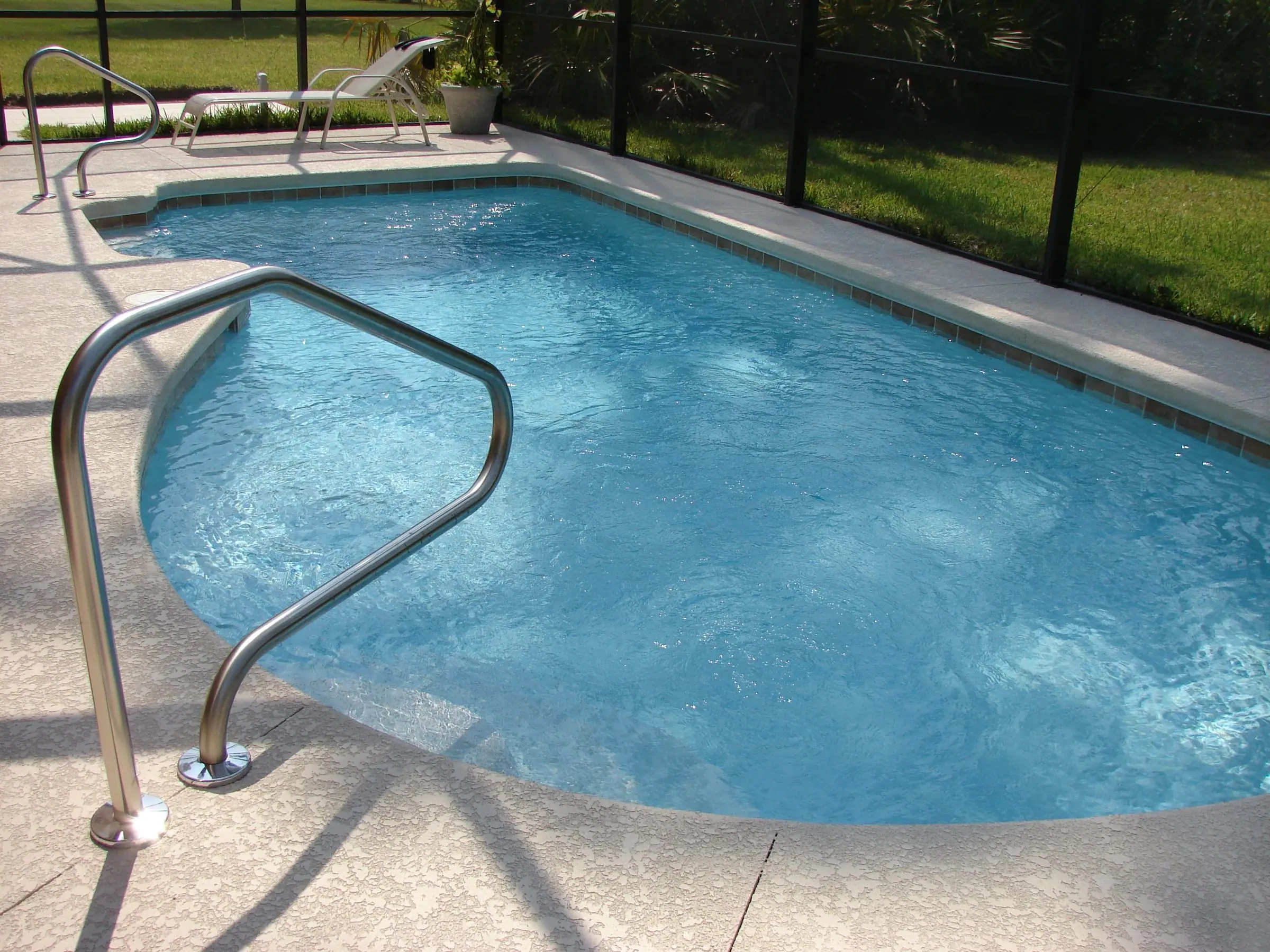 Small backyard pool with a light deck and a hand rail