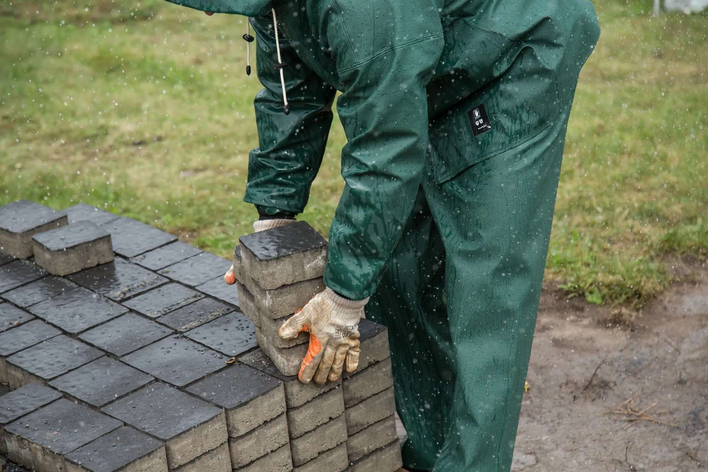 Worker carrying a stack of gray concrete pavers